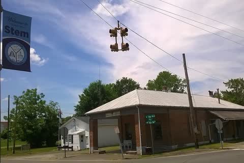 A low brick building at an intersection in Stem, with a town banner on a light pole