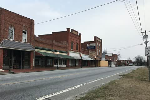 Row of old brick commercial buildings beside a two-lane road in Stokesdale
