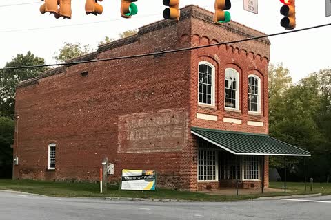 Two-story brick store building with a faded painted sign at a crossroads in Summerfield