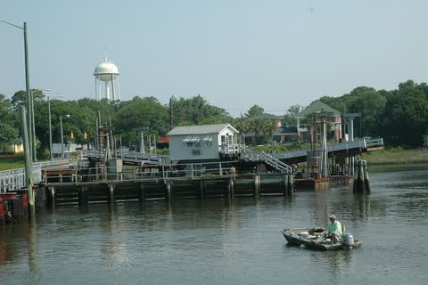 Docks and a small bridge over the waterway at Sunset Beach, with a water tower behind
