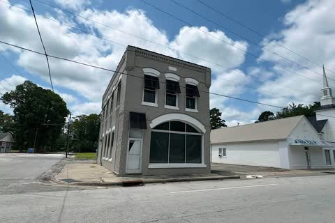 A small gray historic commercial building with arched windows at a corner in Trenton