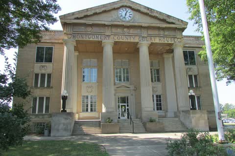 The Montgomery County Courthouse in Troy, columned stone with a clock in the pediment, among trees