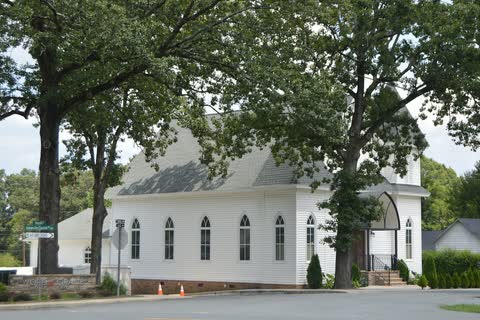 Word of Grace Bible Church in Unionville, a white wooden church with arched windows beneath large oak trees