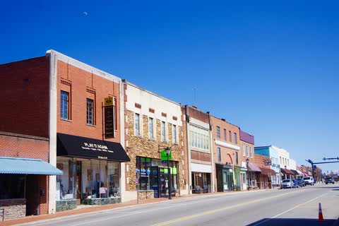 Colorful row of brick storefronts along Main Street in Valdese under a blue sky