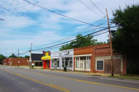 Row of small storefronts beside a two-lane highway in Wagram
