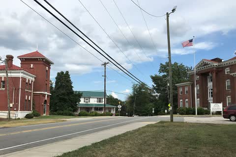 Two historic red brick buildings on either side of a road in Wentworth