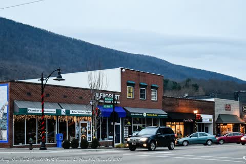 Storefronts along a downtown street in West Jefferson with a mountain behind