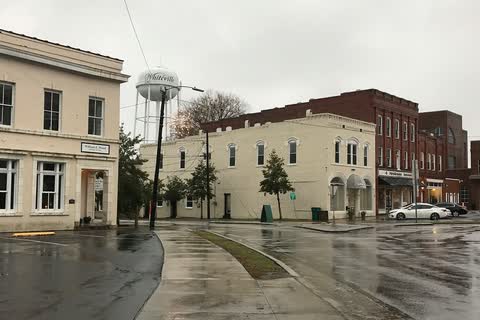 Downtown buildings around the courthouse square in Whiteville, with the water tower behind