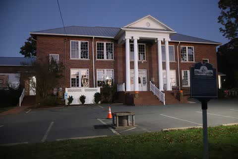 Whitsett Town Hall, a brick building with a white columned portico, photographed at dusk