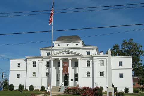 White neoclassical old Wilkes County Courthouse with columns and a flagpole in Wilkesboro