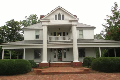 Wingate Town Hall, a white two-story building with a columned front porch and shrubs