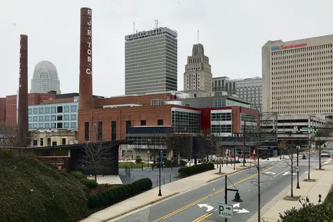 Brick power plant buildings with tall smokestacks in front of downtown Winston-Salem office towers
