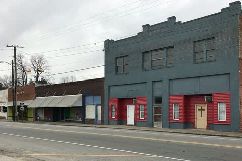 A gray two-story commercial building and storefronts along a street in Woodland