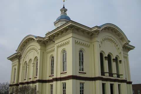 The cream-colored Caswell County Courthouse in Yanceyville, with arched windows and a blue cupola, under a gray sky